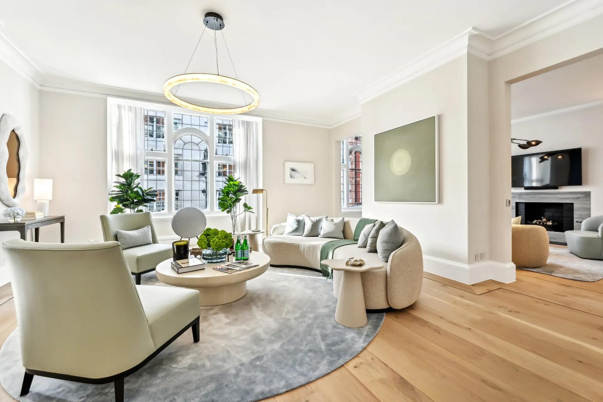 Bright living room with curved sofa, armchairs, round coffee table, and large arched window.