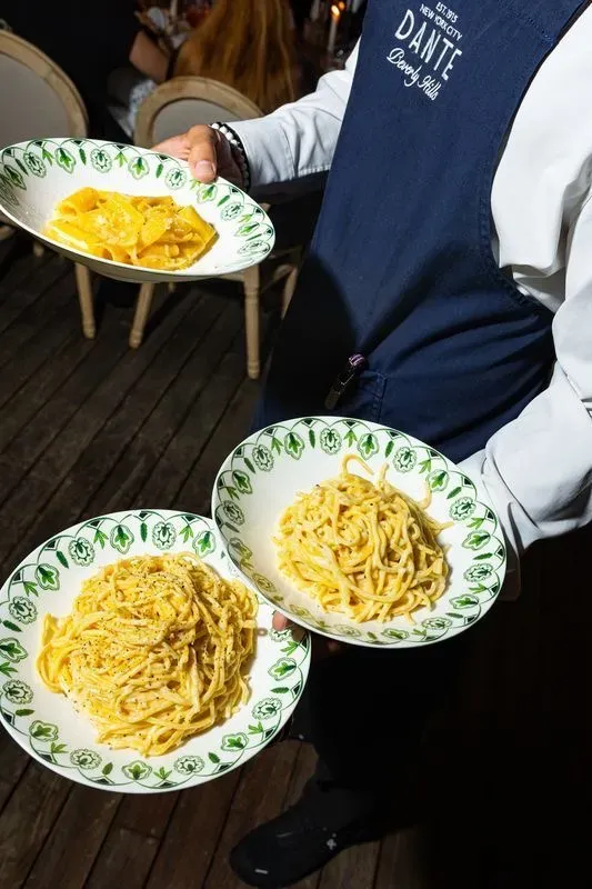 Server holding three plates of fresh made pasta dishes at Dante Beverly Hills.