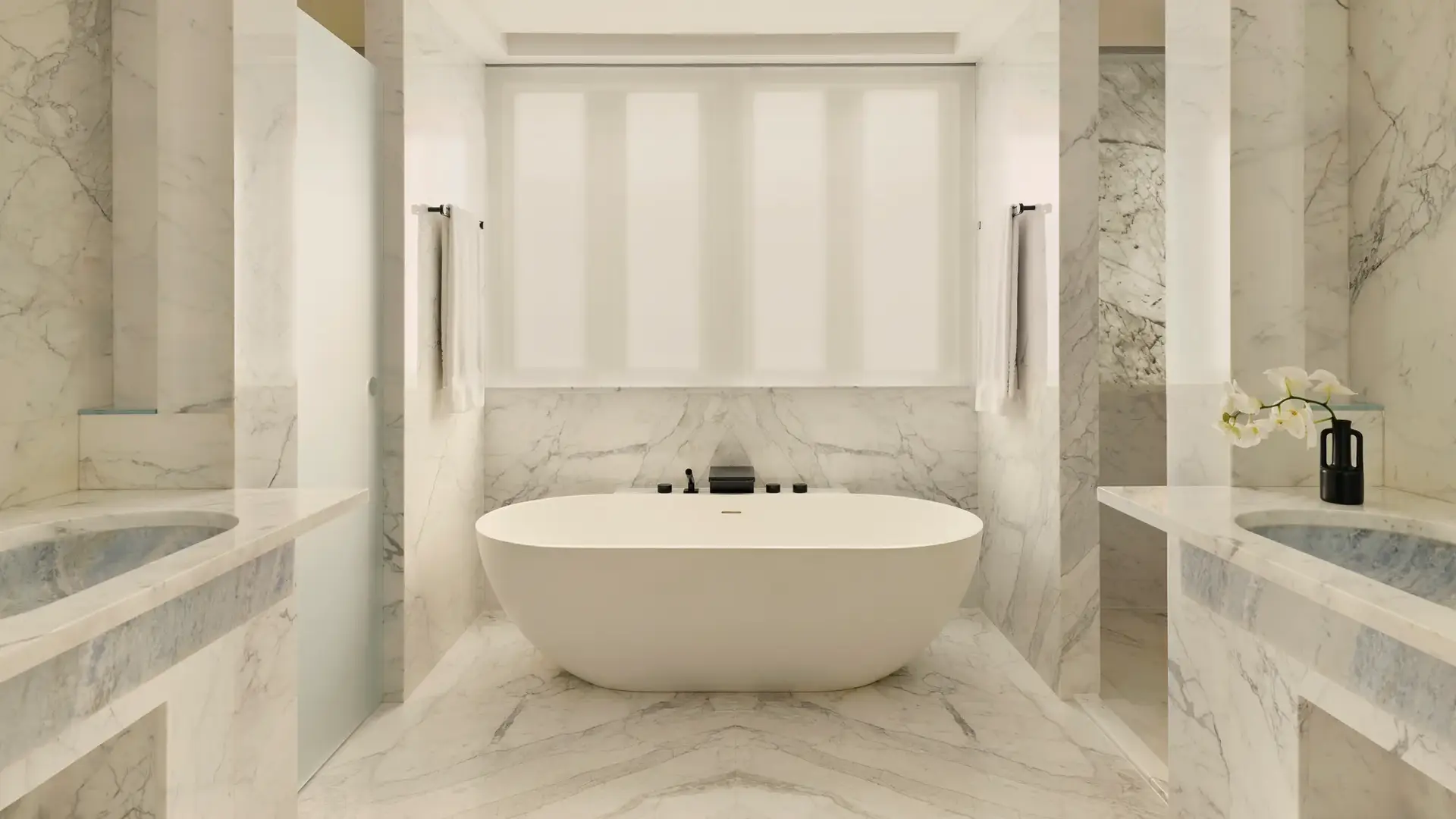 Luxurious marble bathroom with freestanding oval tub, double sinks, and soft natural light.