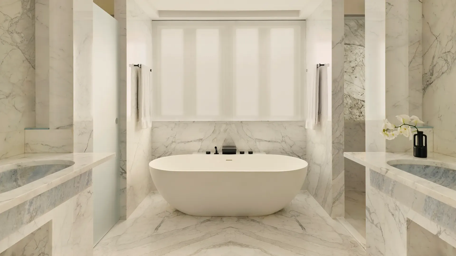 Luxurious marble bathroom with freestanding oval tub, double sinks, and soft natural light.