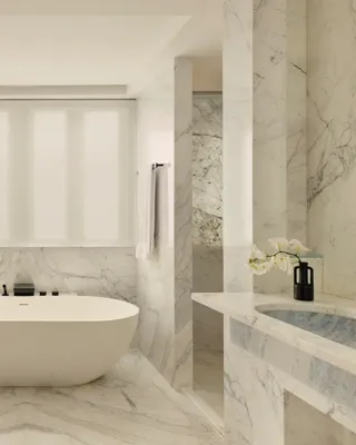 Luxurious marble bathroom with freestanding oval tub, double sinks, and soft natural light.