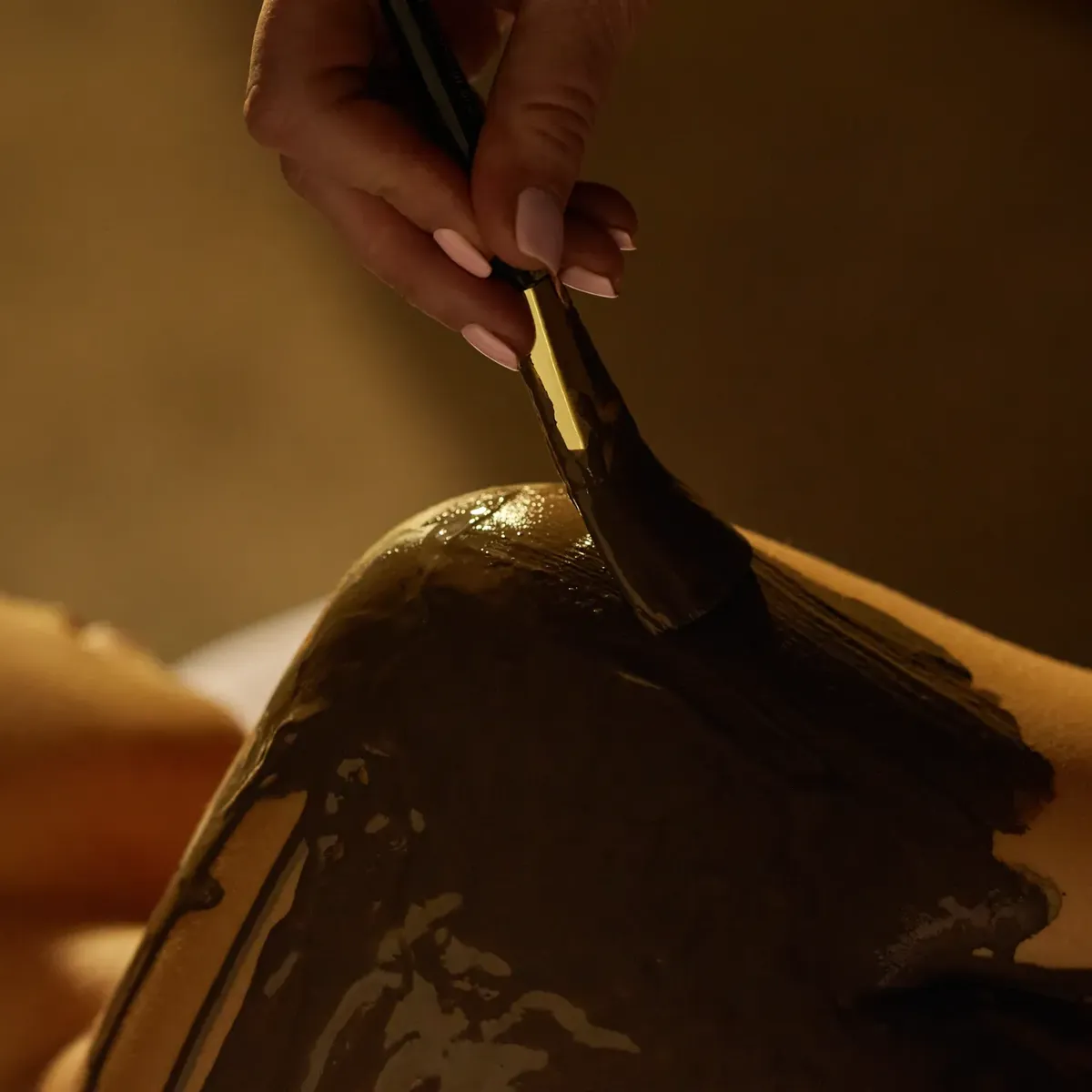 Close-up of therapist applying mineral-rich body mask with brush during spa treatment at The Maybourne Beverly Hills