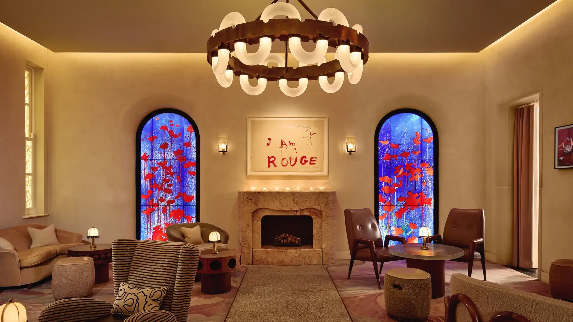 Lounge with fireplace, large circular chandelier, and two blue stained-glass windows with red accents.