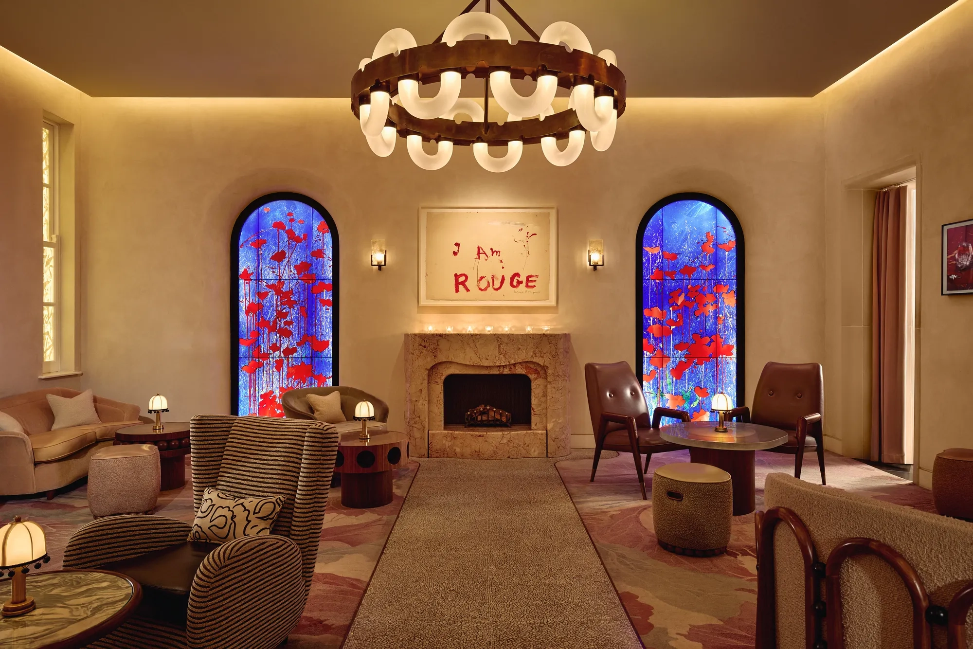 Lounge with fireplace, large circular chandelier, and two blue stained-glass windows with red accents.