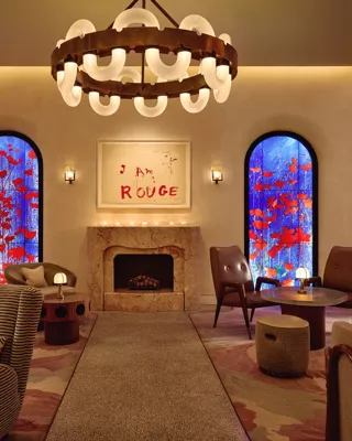 Lounge with fireplace, large circular chandelier, and two blue stained-glass windows with red accents.