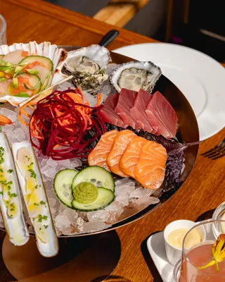 	Plate of sashimi featuring sliced raw fish arranged in rows with garnish on the side.
