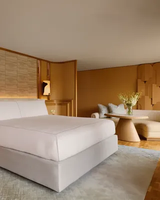 Penthouse bedroom with king bed, wood-panelled walls, curved sofa, and soft lighting