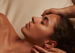Woman receiving a relaxing spa massage, therapist’s hands supporting her head and neck.