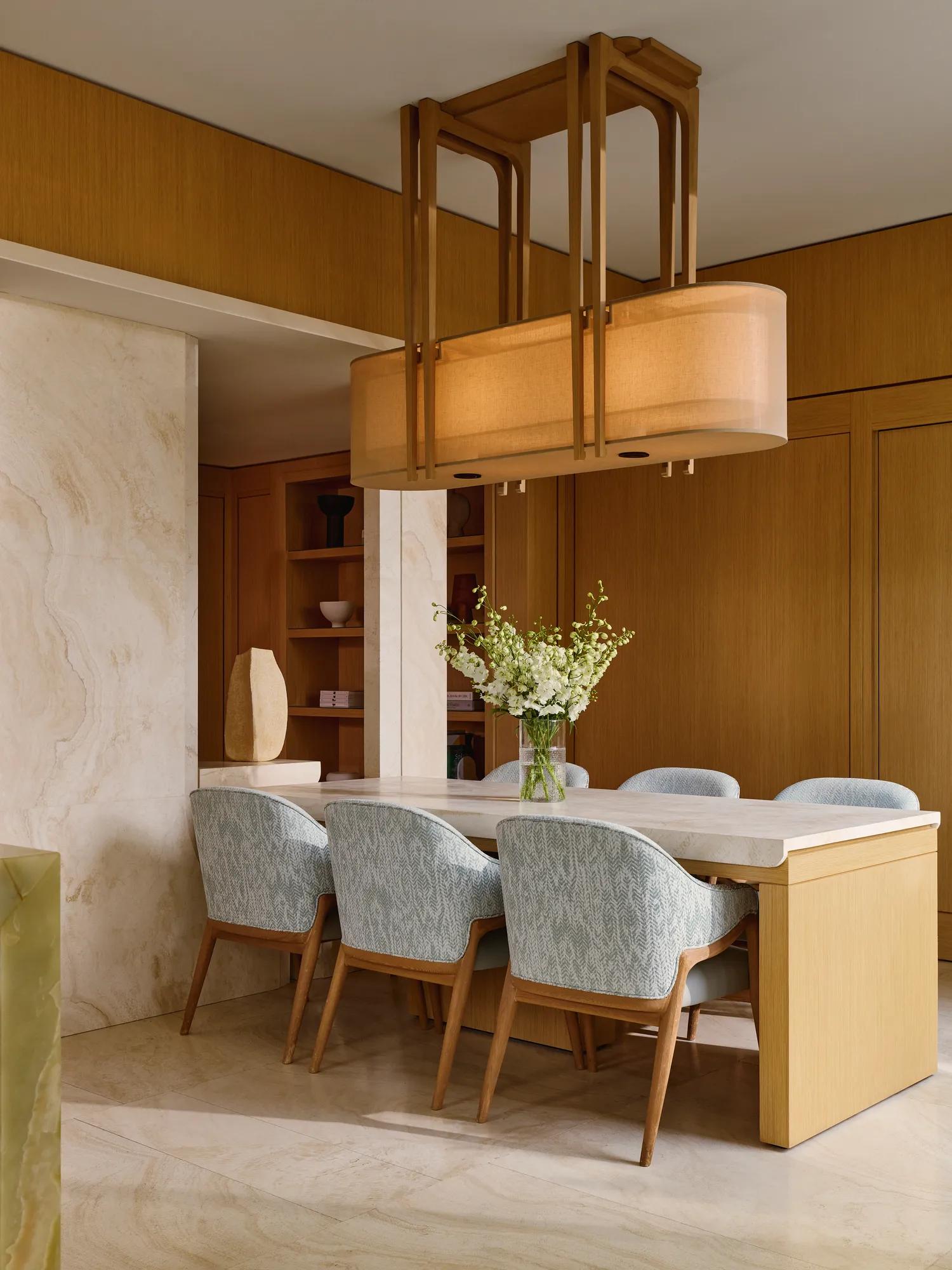 Dining space with light wood table, patterned chairs, and modern pendant lighting in the penthouse.