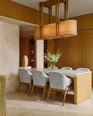 Dining space with light wood table, patterned chairs, and modern pendant lighting in the penthouse.