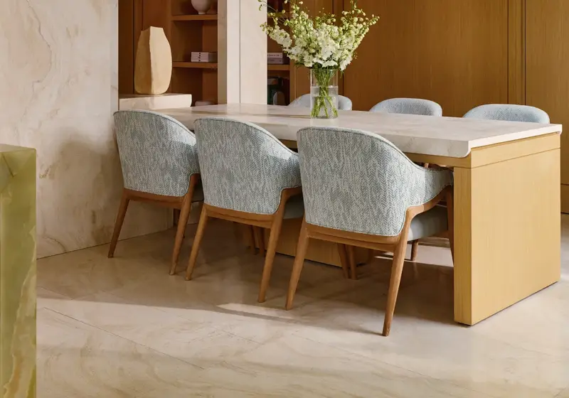 Dining space with light wood table, patterned chairs, and modern pendant lighting in the penthouse.