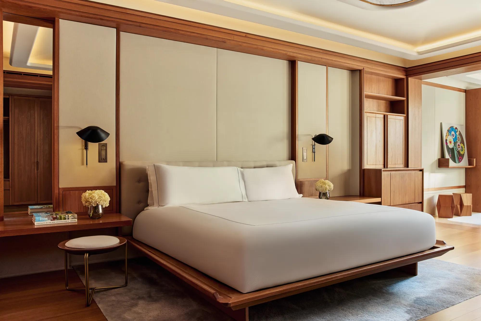 Spacious bedroom with minimalist king bed, wooden details, and soft ambient lighting.