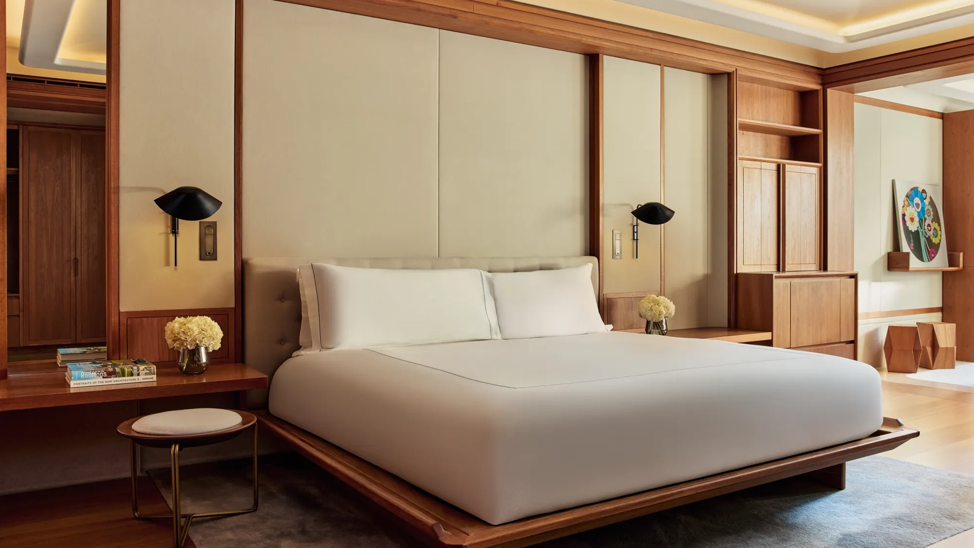 Spacious bedroom with minimalist king bed, wooden details, and soft ambient lighting.