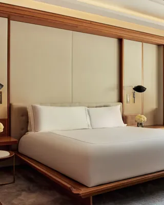 Spacious bedroom with minimalist king bed, wooden details, and soft ambient lighting.