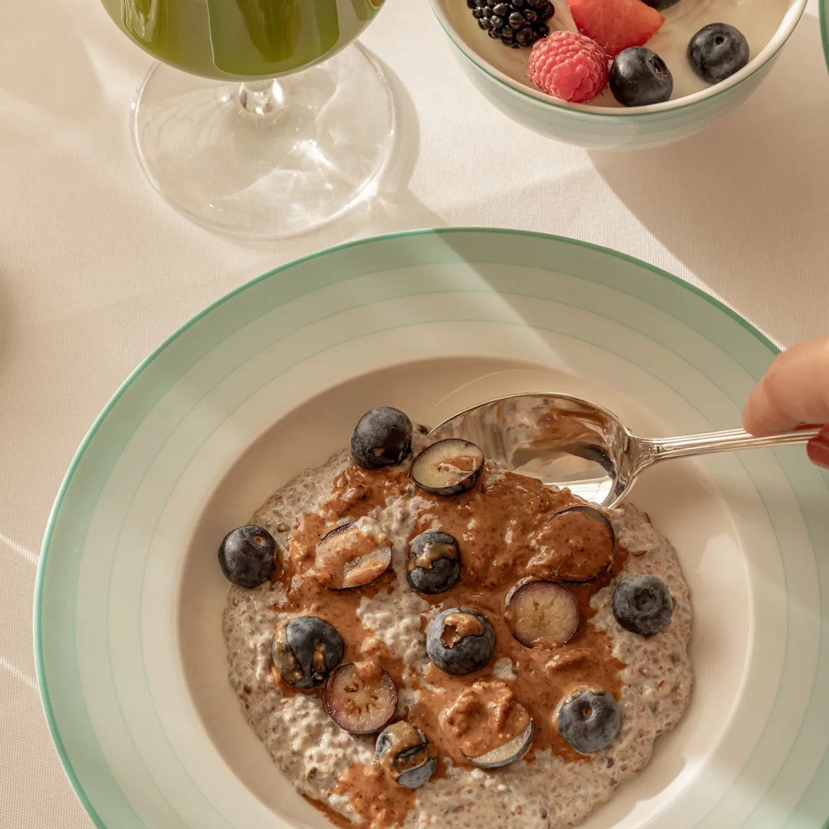 Bowl of chia pudding topped with blueberries and nut butter, spoon lifting a bite.