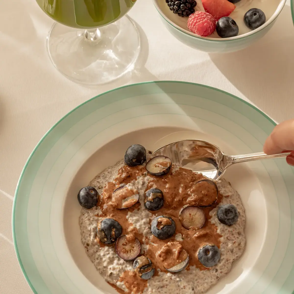 Bowl of chia pudding topped with blueberries and nut butter, spoon lifting a bite.
