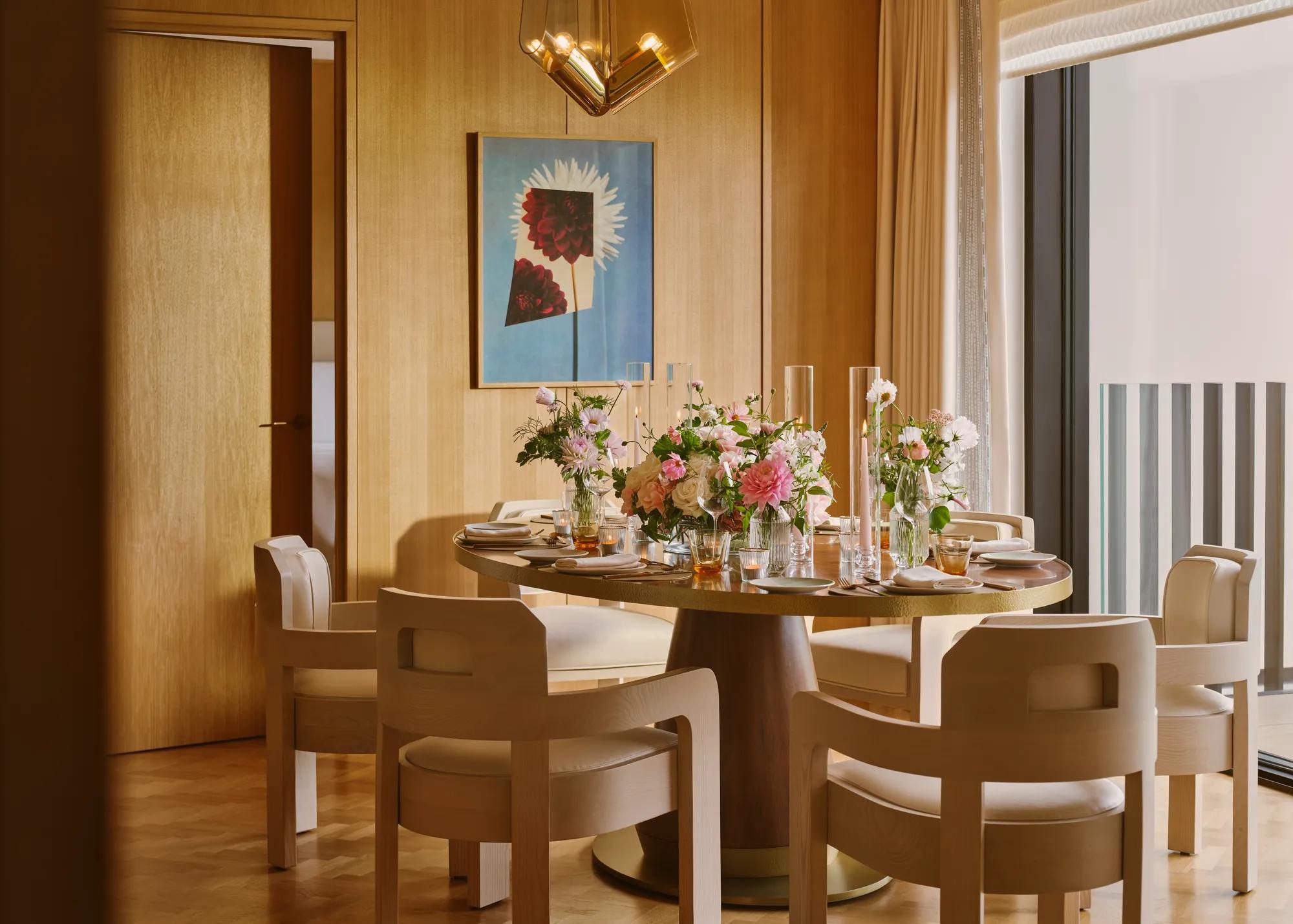 Private dining room set for an elegant meal with floral centrepieces, soft lighting and mid-century modern chairs