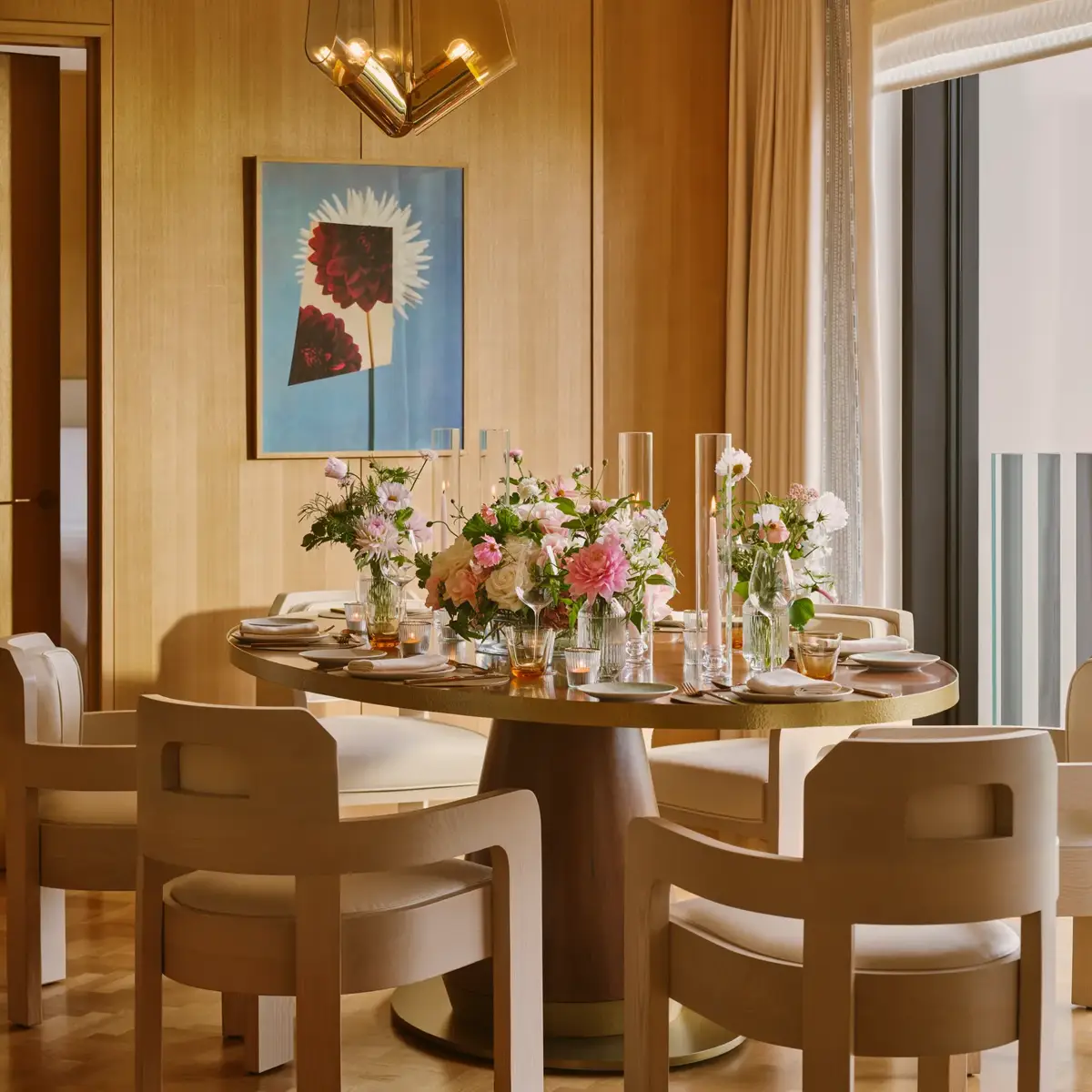 Private dining room set for an elegant meal with floral centrepieces, soft lighting and mid-century modern chairs
