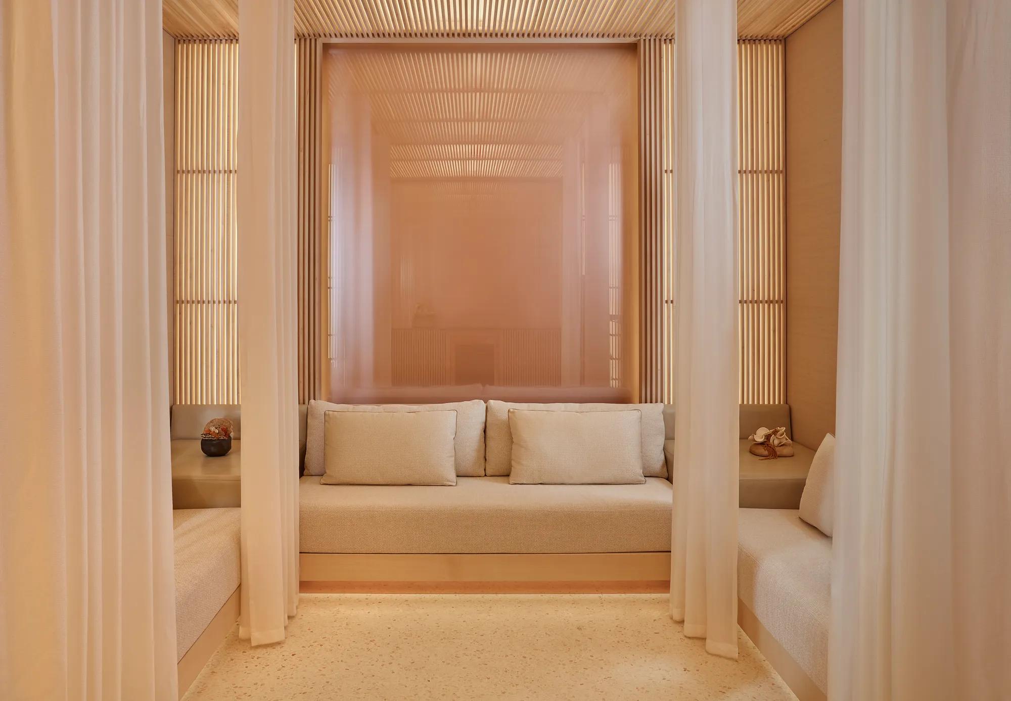 Private spa cabana with cream seating, soft cushions, and sheer curtains creating a serene, relaxing space