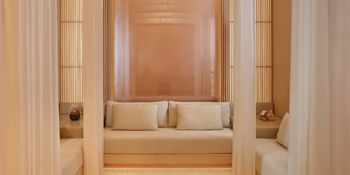 Private spa cabana with cream seating, soft cushions, and sheer curtains creating a serene, relaxing space