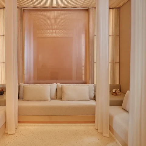 Private spa cabana with cream seating, soft cushions, and sheer curtains creating a serene, relaxing space