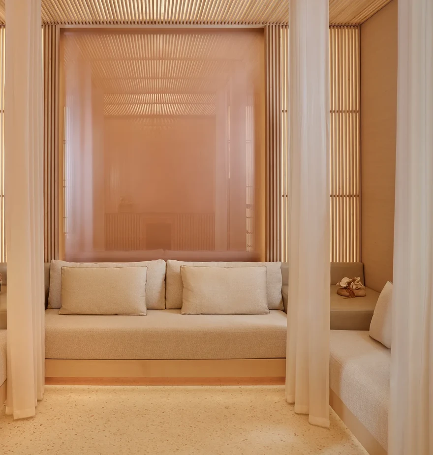 Private spa cabana with cream seating, soft cushions, and sheer curtains creating a serene, relaxing space