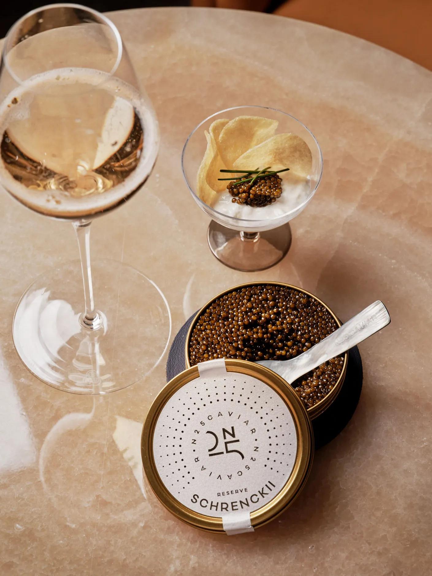 Glass of champagne served with caviar tin, potato chips, and crème fraîche at Maybourne Beverly Hills.