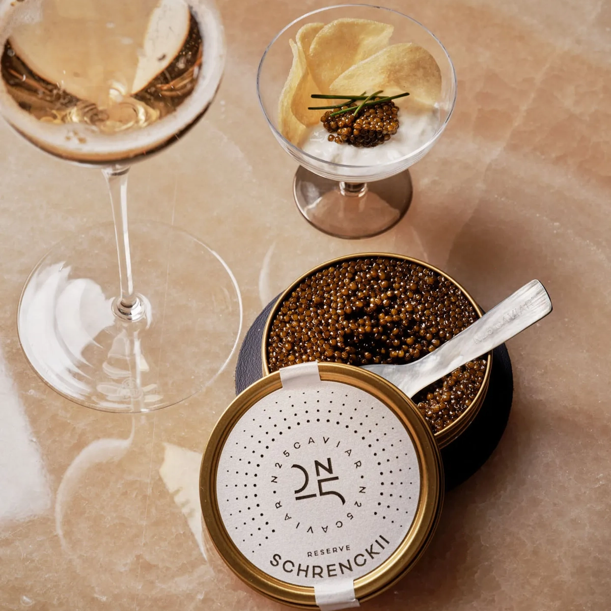 Glass of champagne served with caviar tin, potato chips, and crème fraîche at Maybourne Beverly Hills.
