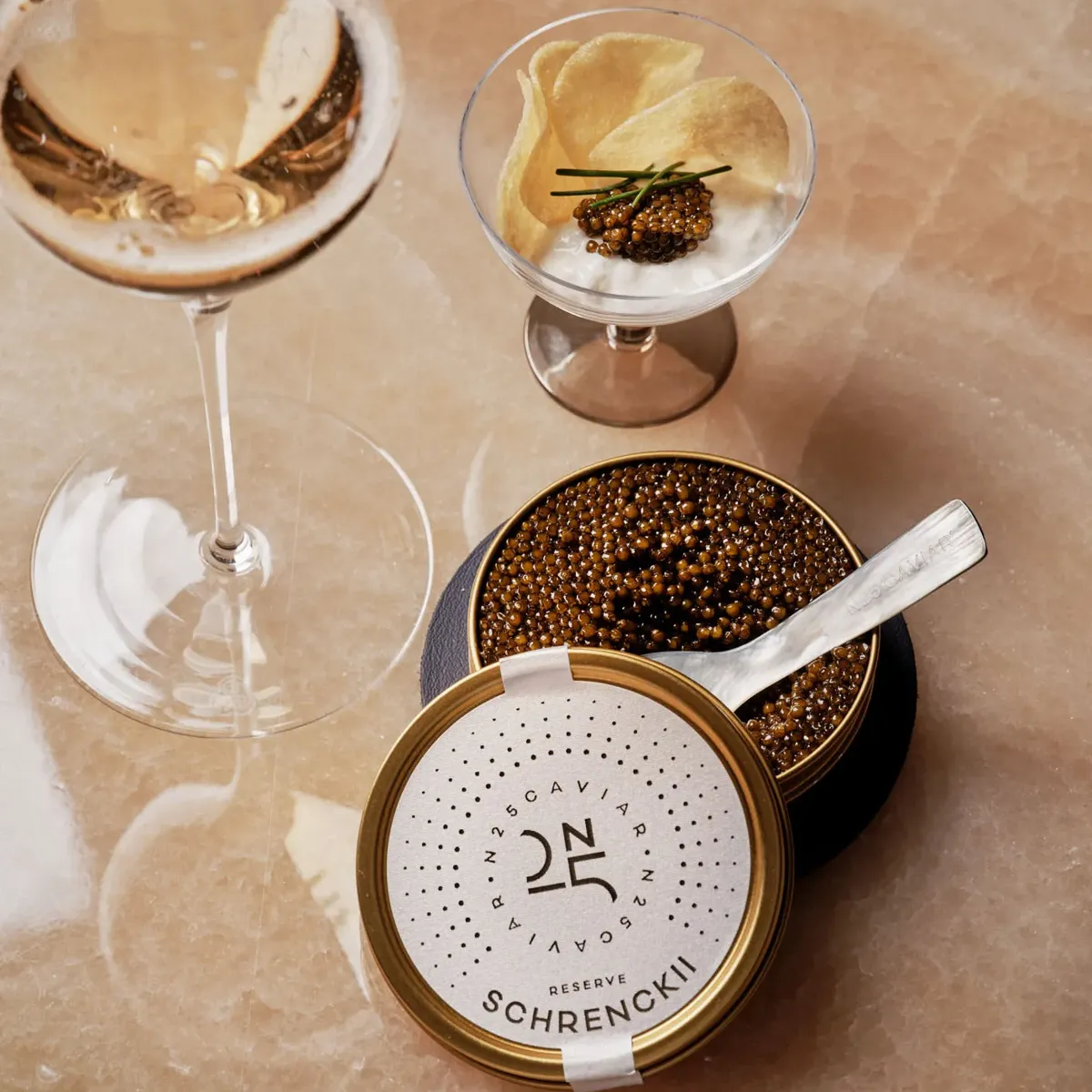 Glass of champagne served with caviar tin, potato chips, and crème fraîche at Maybourne Beverly Hills.