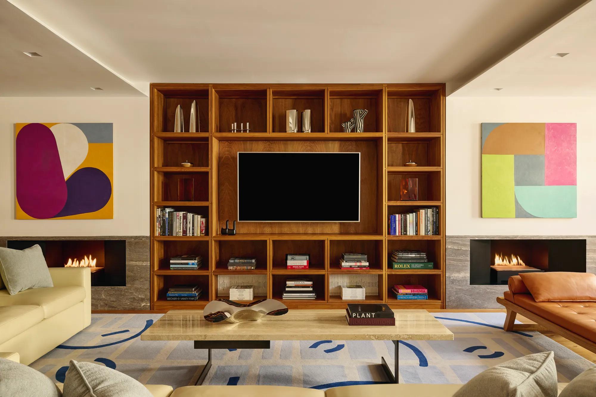 Contemporary living room with wood shelving, modern art, twin fireplaces, and cream sofas.