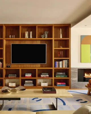 Contemporary living room with wood shelving, modern art, twin fireplaces, and cream sofas.