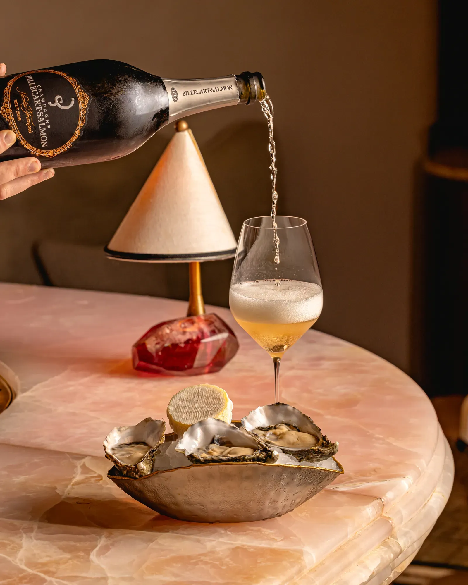 A bottle of champagne tilted over a flute as sparkling wine pours in, creating bubbles that rise to the surface.