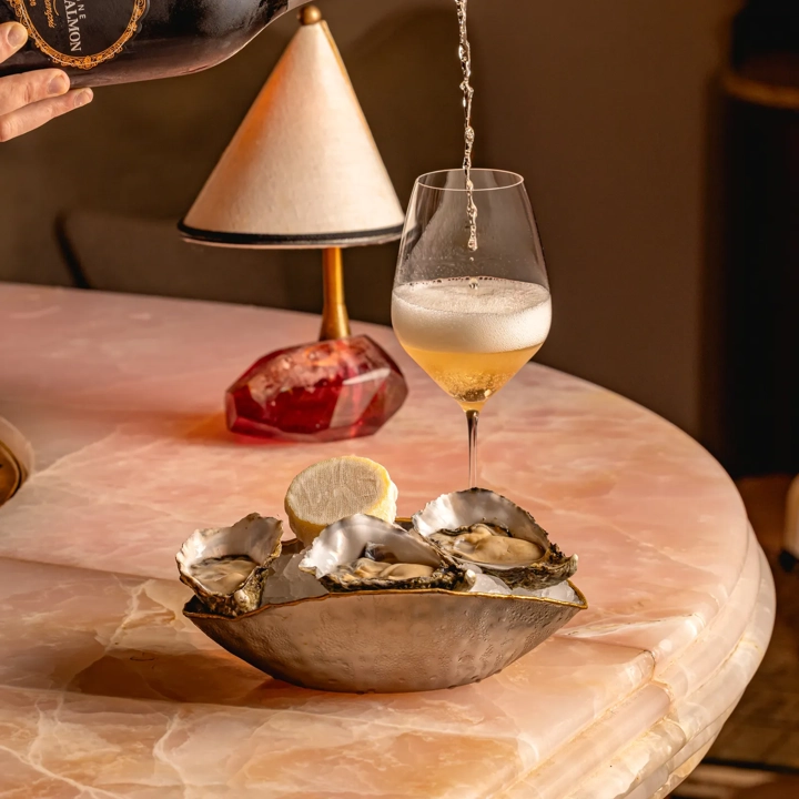 A bottle of champagne tilted over a flute as sparkling wine pours in, creating bubbles that rise to the surface.