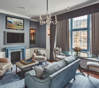 Elegant living room with blue fireplace, chandelier, seating area, and large window.