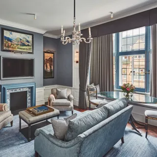 Elegant living room with blue fireplace, chandelier, seating area, and large window.