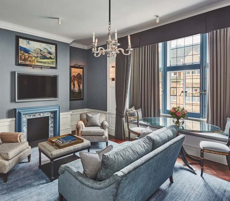 Elegant living room with blue fireplace, chandelier, seating area, and large window.
