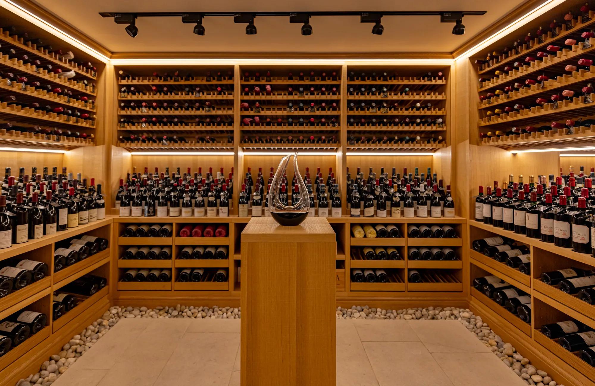 Elegant wine cellar lined with wooden racks filled with bottles and a central display pedestal.