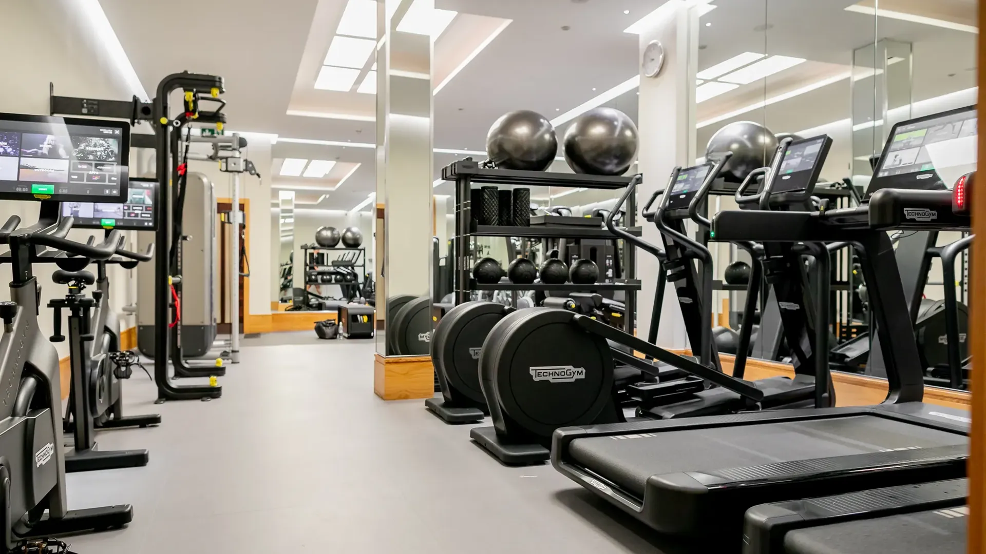 	Bright gym room featuring cardio machines, free weights, and open floor space for training.
