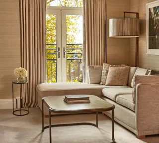 Elegant lounge with corner sofa, coffee table, and French doors opening to a Juliet balcony.