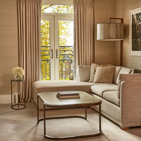 Elegant lounge with corner sofa, coffee table, and French doors opening to a Juliet balcony.