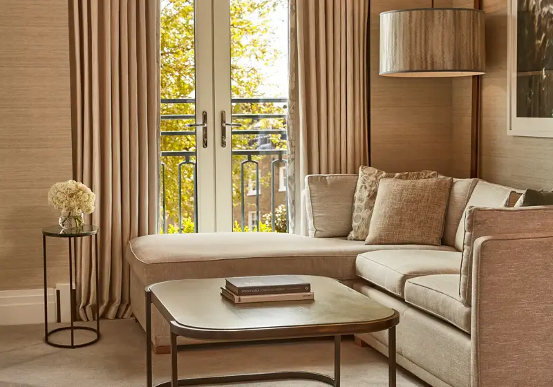 Elegant lounge with corner sofa, coffee table, and French doors opening to a Juliet balcony.