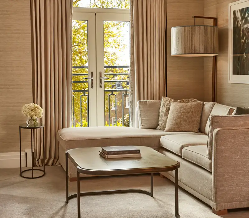 Elegant lounge with corner sofa, coffee table, and French doors opening to a Juliet balcony.