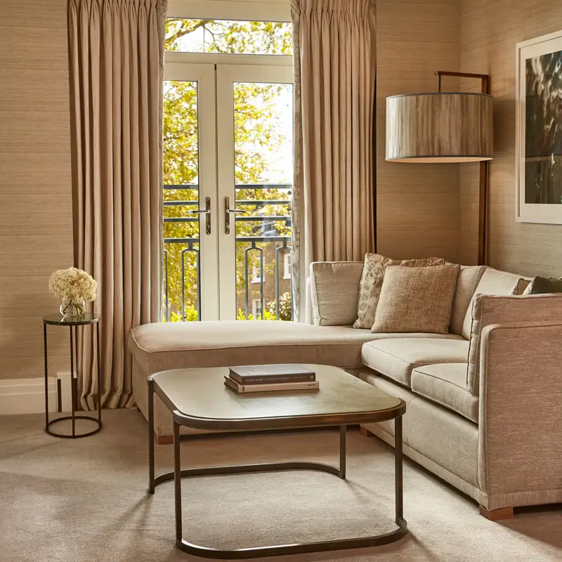 Elegant lounge with corner sofa, coffee table, and French doors opening to a Juliet balcony.