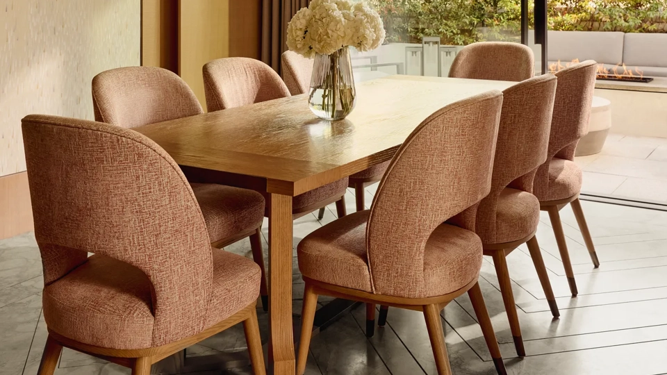 Dining room with wooden table, pink upholstered chairs, and modern glass pendant chandelier, opening to terrace