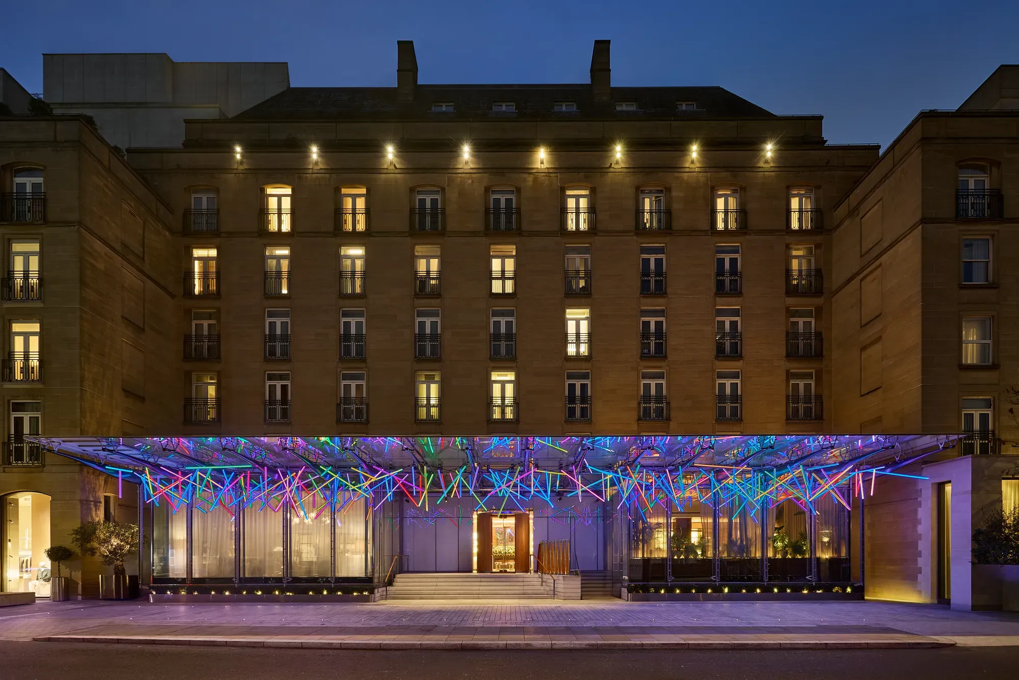 The Berkeley’s illuminated glass canopy glows with vibrant colours at night above the hotel’s entrance on Wilton Place.