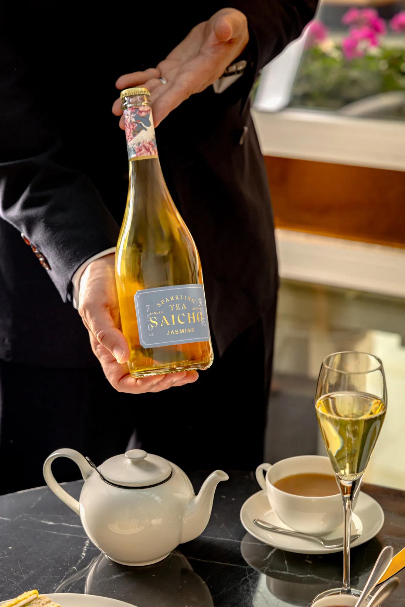 **Alt text:**
Bottle of Saicho Jasmine sparkling tea presented beside a teapot, teacup and filled flute on an afternoon tea table.
