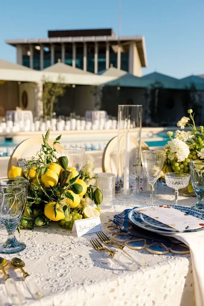 Rooftop poolside dining setup in Beverly Hills with citrus centerpieces and blue patterned plates.