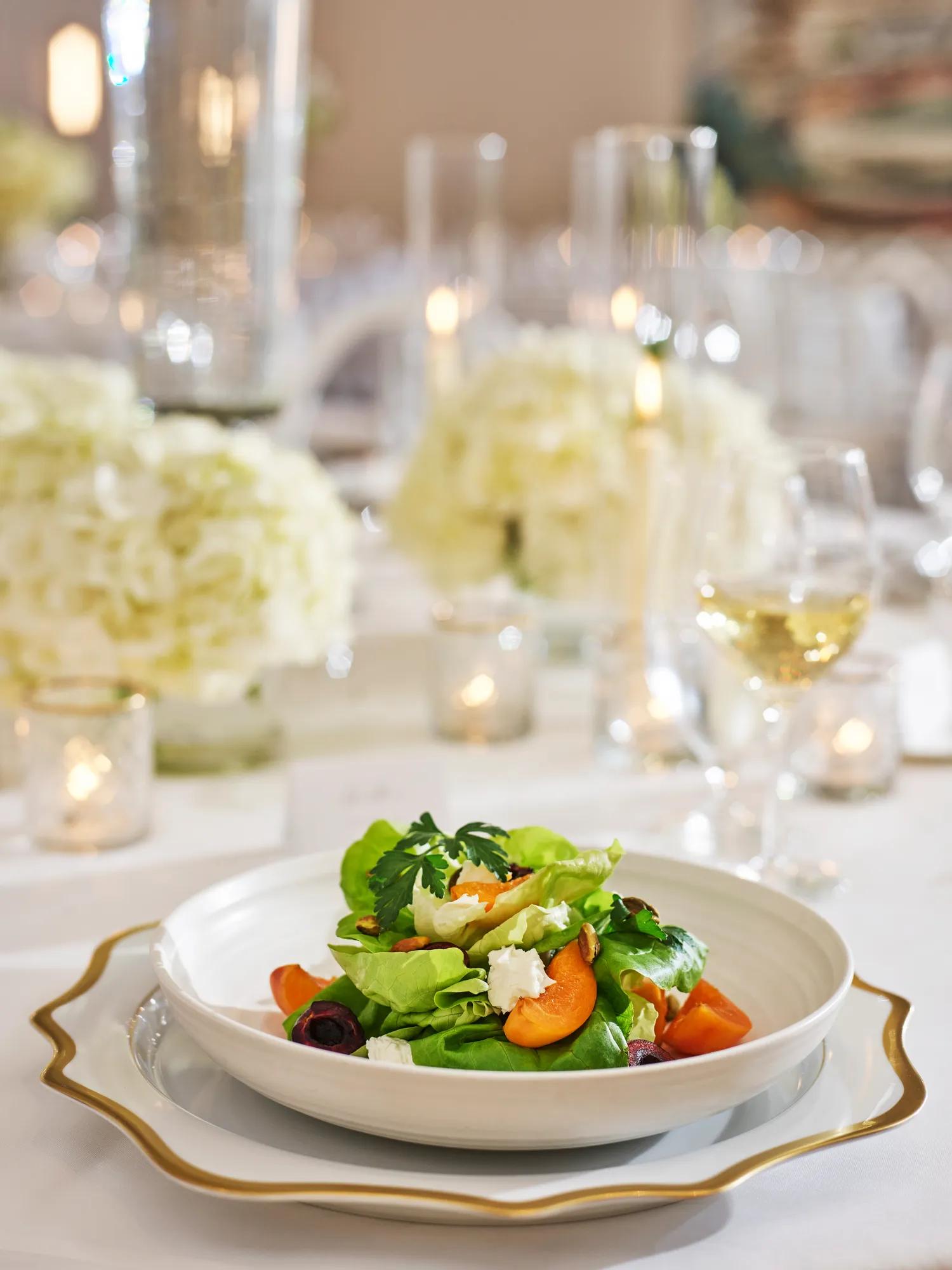 Butter-lettuce salad with apricots, goat cheese, and pistachios on fine china.