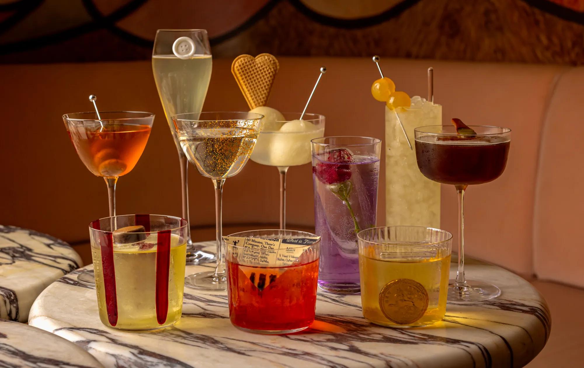 A mix of cocktails of different colours featured on a marble table.