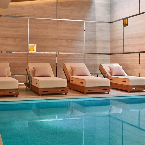 A serene spa setting featuring soft ambient lighting, neatly rolled towels, and natural elements like candles and smooth stones arranged on a wooden surface, creating a calm and relaxing atmosphere.